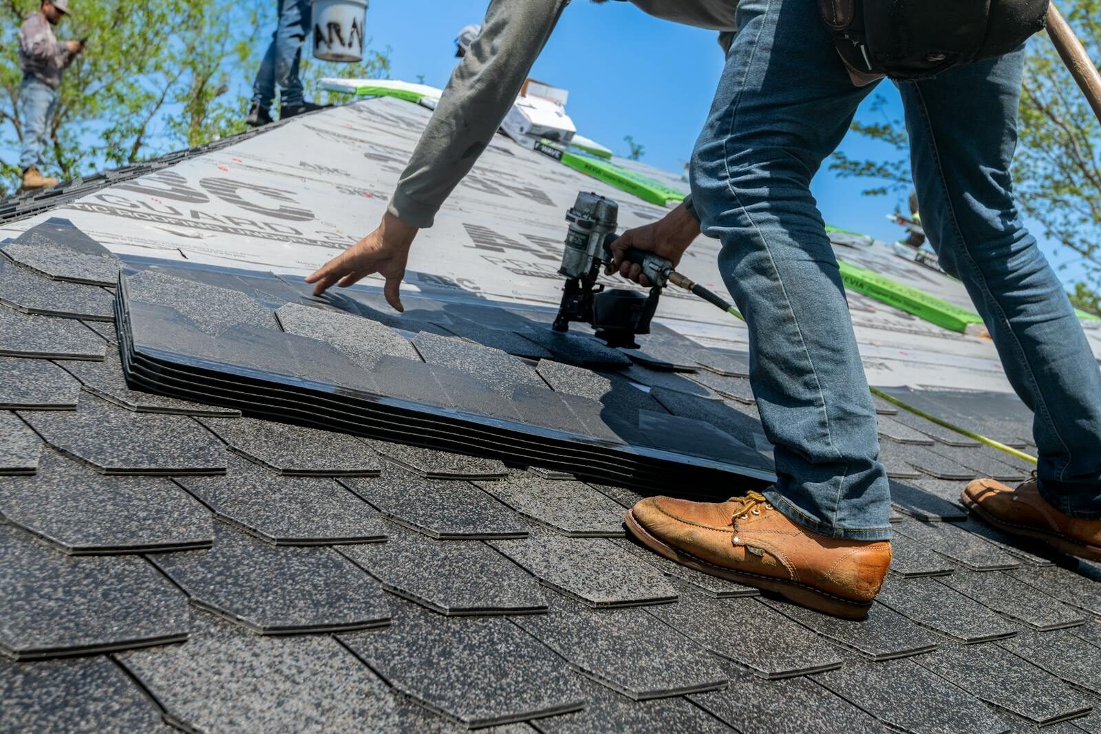 Roofer installing shingle on residential roof.